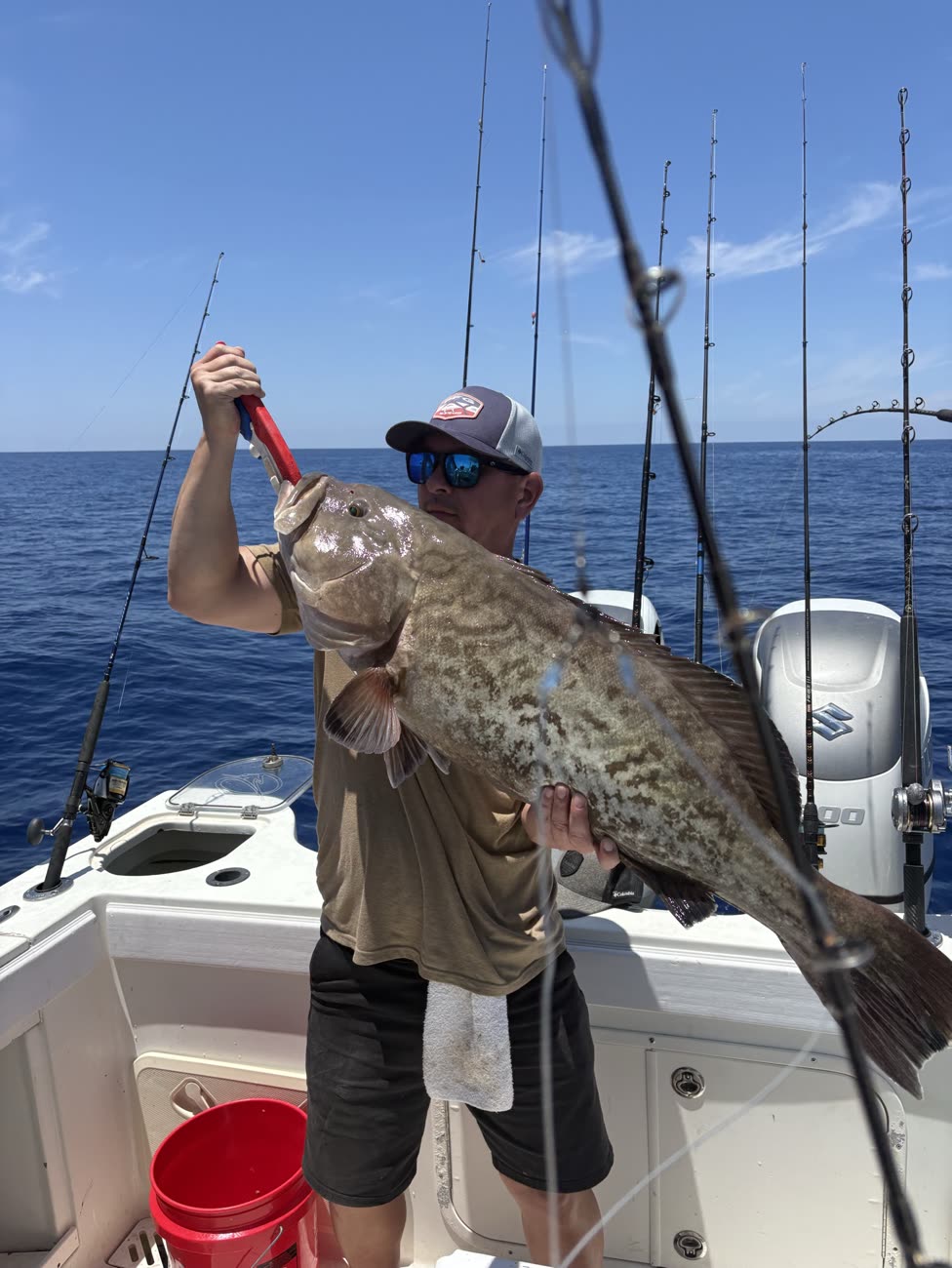 Angler holding a 20-pound-class gag grouper with the Suzuki 300 outboard behind