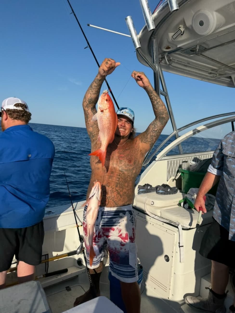 Angler swinging a vermilion snapper aboard in golden evening light